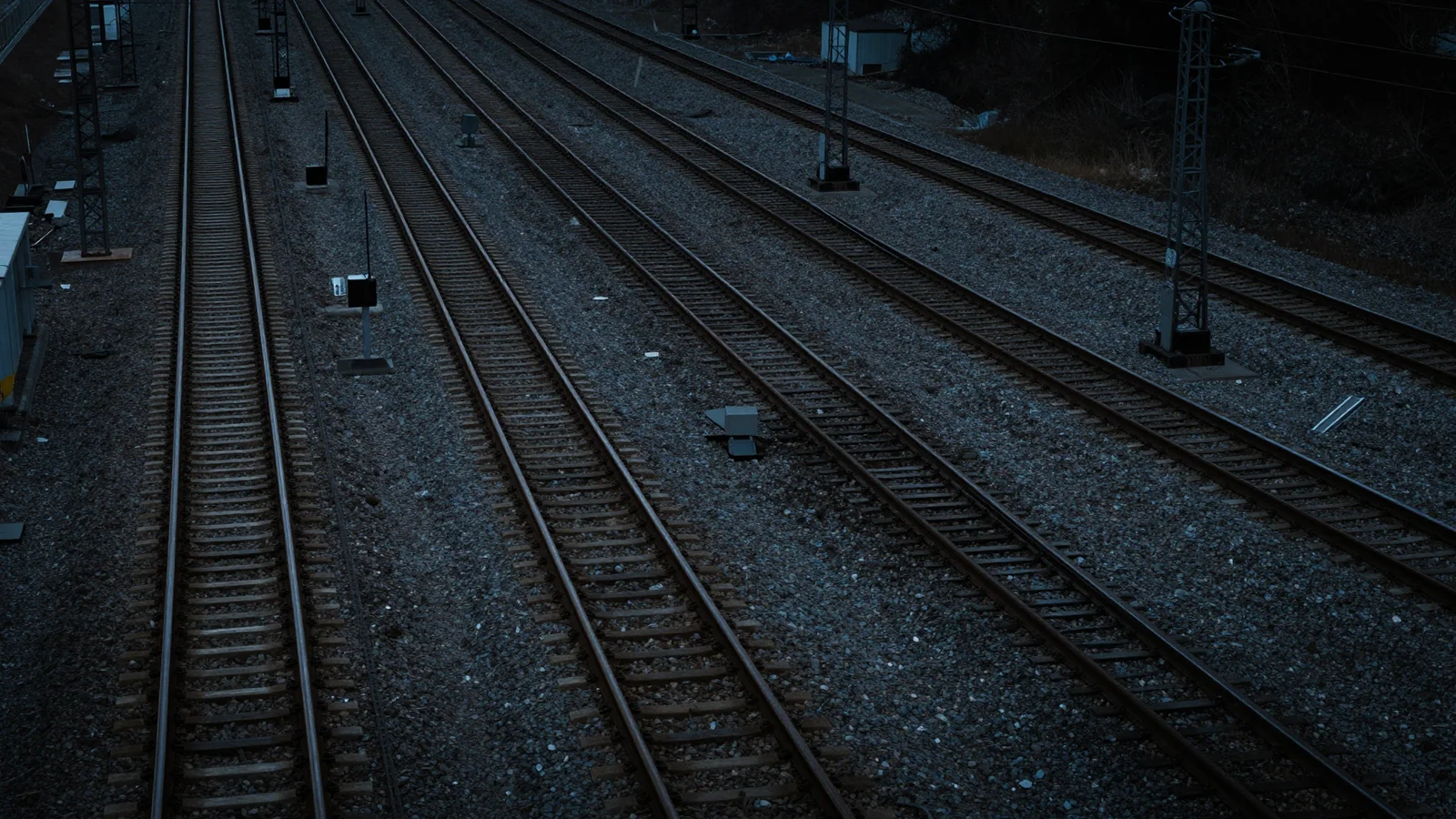 An elevated view across parallel railway tracks and switch equipment on grey gravel.