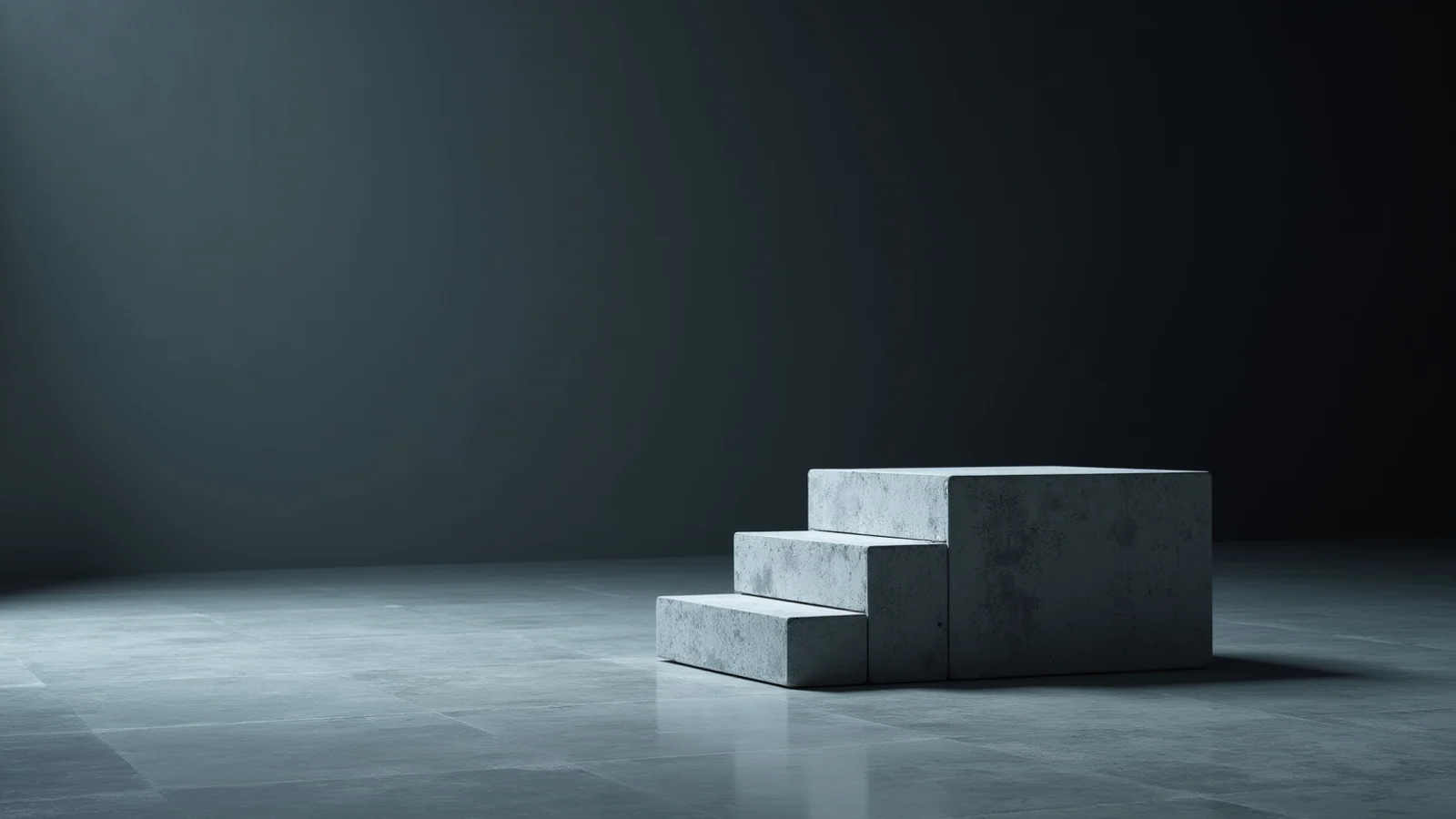A block of pale grey concrete cast as two steps, the upper step twice the height of the lower, in an empty grey room.